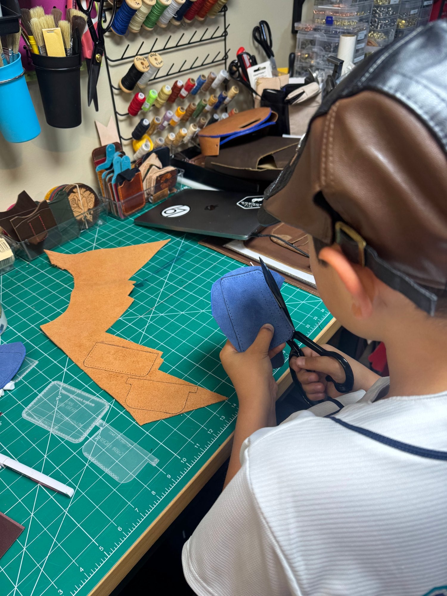 Cutting leather shapes by hand at the workbench.